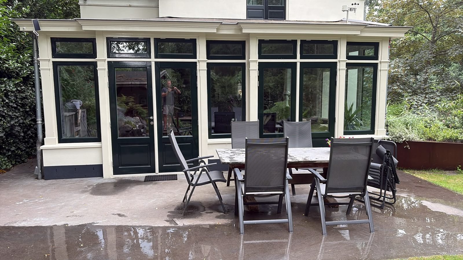 Orangerie met donkergroene kozijnen en openslaande tuindeuren aan een terras